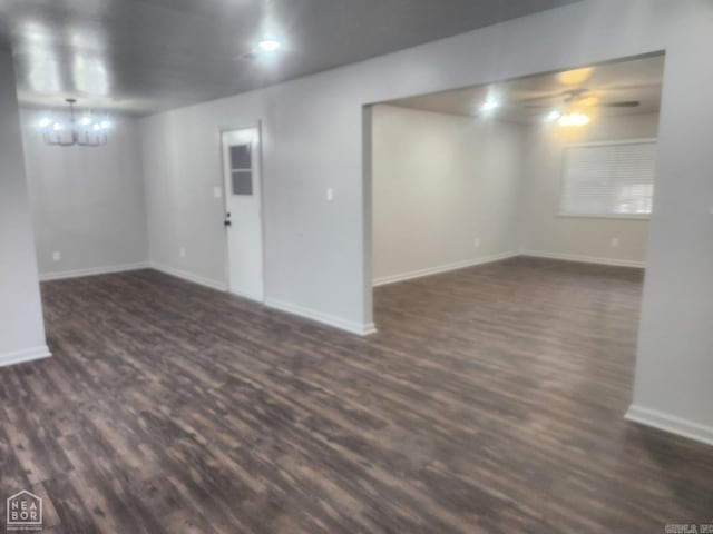 basement with ceiling fan with notable chandelier and dark hardwood / wood-style flooring