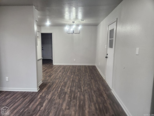 spare room featuring a notable chandelier, dark hardwood / wood-style floors, and a textured ceiling