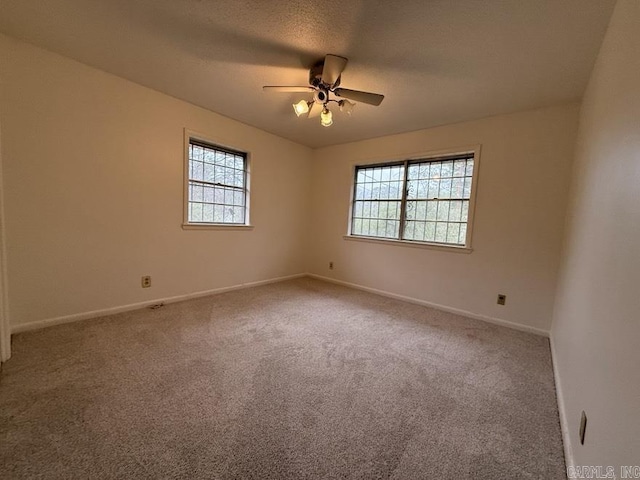 unfurnished room with carpet, ceiling fan, a textured ceiling, and a wealth of natural light