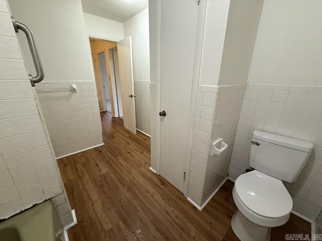 bathroom with hardwood / wood-style flooring, toilet, and tile walls