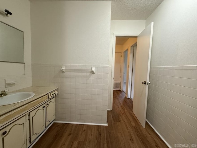 bathroom with hardwood / wood-style flooring, vanity, tile walls, and a textured ceiling