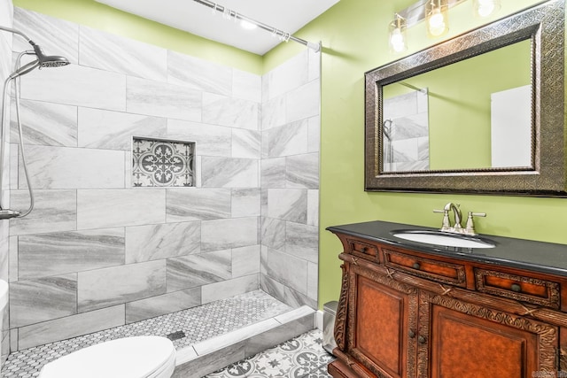 bathroom with tiled shower, vanity, toilet, and tile patterned flooring