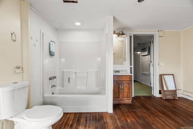 full bathroom featuring hardwood / wood-style floors, vanity, an AC wall unit, toilet, and shower / bathtub combination