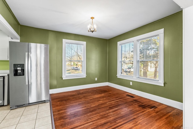 unfurnished dining area with light tile patterned floors and an inviting chandelier