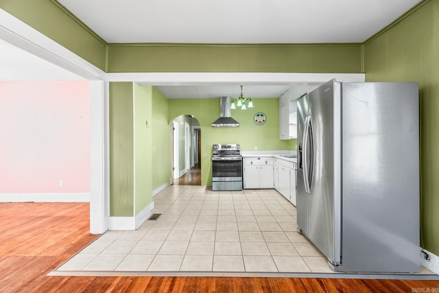 kitchen with a chandelier, light hardwood / wood-style flooring, stainless steel appliances, and wall chimney range hood