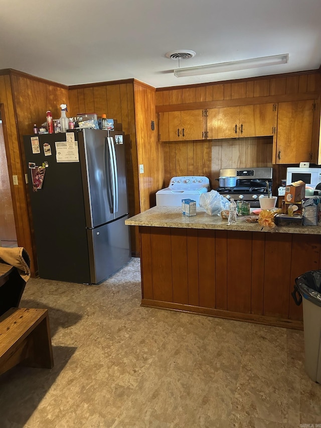 kitchen featuring wooden walls, washer / clothes dryer, kitchen peninsula, and appliances with stainless steel finishes