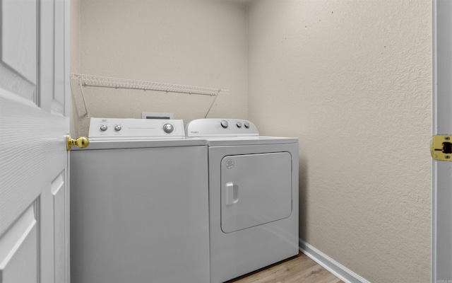 laundry room featuring washer and clothes dryer and light hardwood / wood-style floors