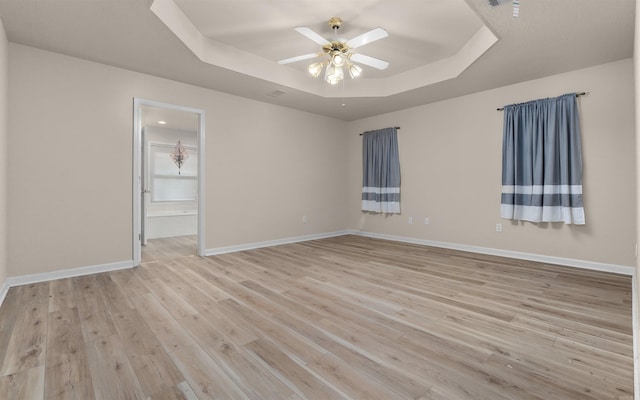 empty room featuring a tray ceiling, light hardwood / wood-style flooring, and ceiling fan