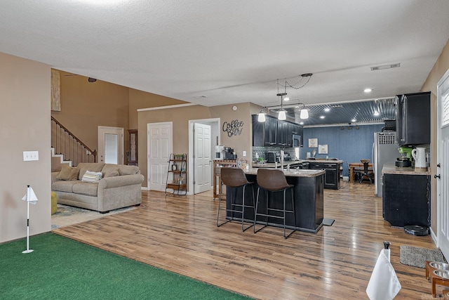 kitchen featuring light countertops, dark cabinetry, a breakfast bar, and visible vents