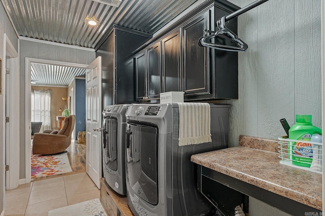 clothes washing area with cabinet space, washer and clothes dryer, and light tile patterned floors