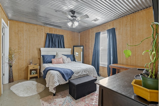 bedroom featuring wood walls, ceiling fan, and concrete flooring