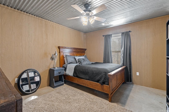 bedroom with a ceiling fan, visible vents, concrete floors, and wooden walls