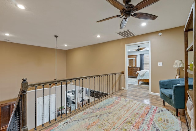 hall featuring baseboards, visible vents, wood finished floors, an upstairs landing, and recessed lighting