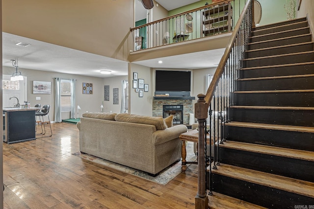 living room featuring visible vents, hardwood / wood-style flooring, a high ceiling, stairs, and a fireplace