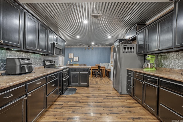 kitchen featuring stainless steel appliances, tasteful backsplash, a peninsula, and dark wood-style floors