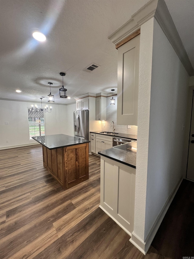 kitchen with stainless steel appliances, sink, pendant lighting, dark hardwood / wood-style floors, and a kitchen island