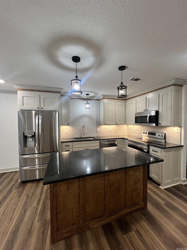 kitchen with appliances with stainless steel finishes, backsplash, dark hardwood / wood-style flooring, sink, and hanging light fixtures