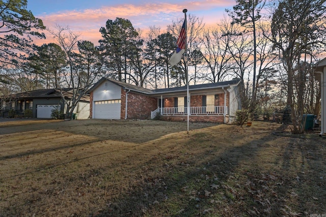 ranch-style house featuring a porch, a garage, and a lawn