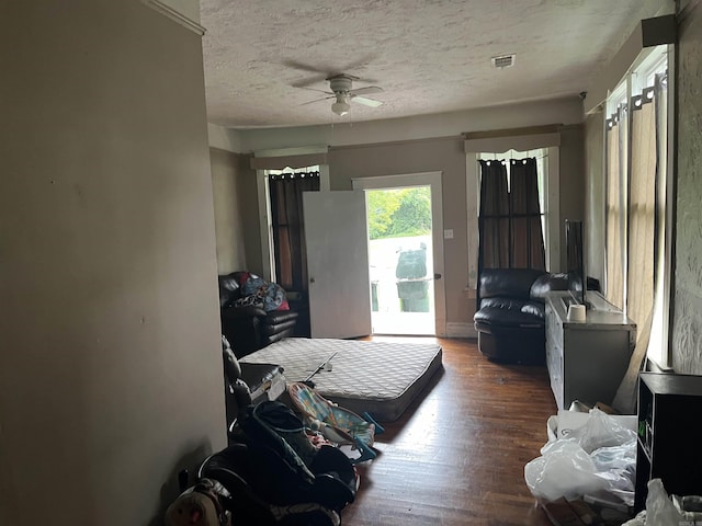 bedroom with a textured ceiling, ceiling fan, dark wood-type flooring, and access to outside