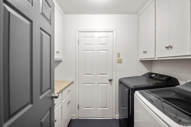 laundry room with dark tile patterned flooring, cabinets, and independent washer and dryer