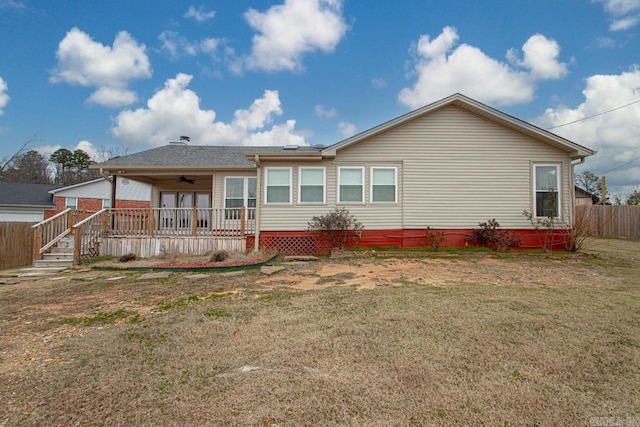 rear view of house with ceiling fan and a lawn