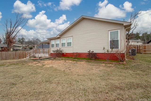 view of side of home featuring a deck, cooling unit, and a lawn