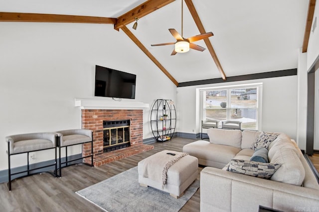 living room featuring hardwood / wood-style floors, high vaulted ceiling, a brick fireplace, ceiling fan, and beam ceiling