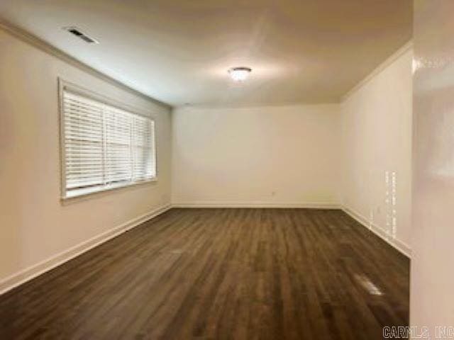 empty room with crown molding and dark hardwood / wood-style flooring