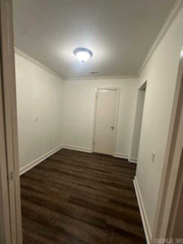 spare room featuring dark wood-type flooring and ornamental molding