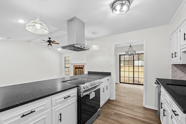 kitchen with stainless steel appliances, lofted ceiling with beams, island range hood, white cabinets, and ceiling fan with notable chandelier