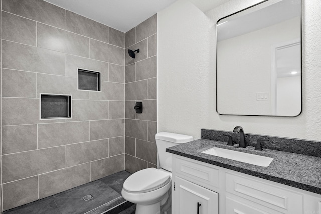 bathroom featuring toilet, vanity, and tiled shower