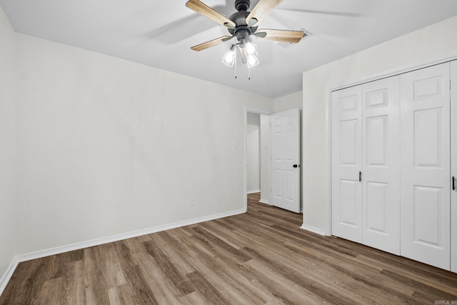 unfurnished bedroom featuring dark hardwood / wood-style flooring, ceiling fan, and a closet