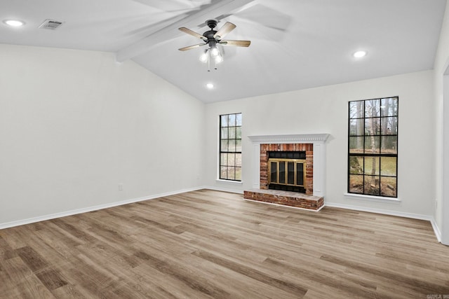 unfurnished living room featuring lofted ceiling with beams, ceiling fan, a fireplace, and a wealth of natural light