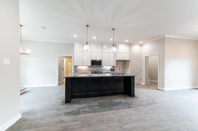 kitchen with pendant lighting, sink, ornamental molding, an island with sink, and white cabinetry