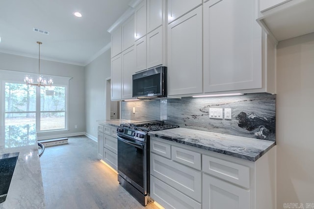 kitchen with black gas range oven, white cabinetry, hanging light fixtures, and ornamental molding