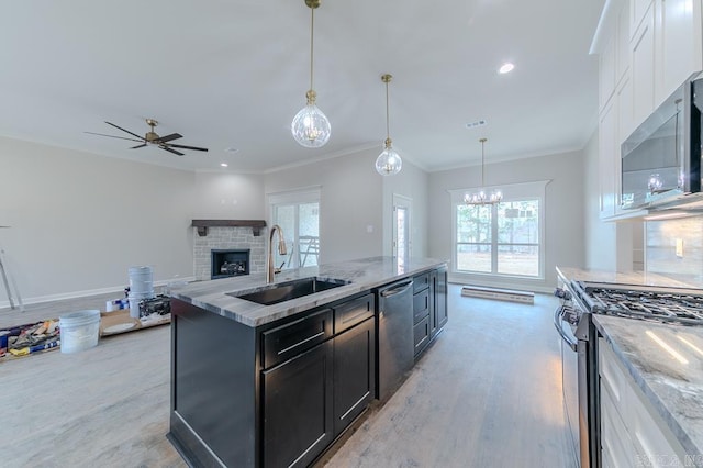 kitchen with light stone countertops, stainless steel appliances, sink, pendant lighting, and white cabinetry