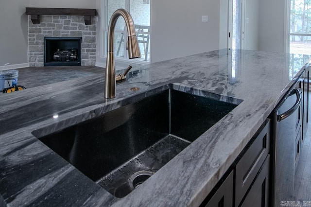 kitchen with a stone fireplace, sink, and stone counters