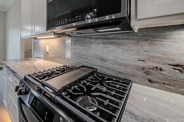 kitchen with tasteful backsplash, white cabinets, and stainless steel appliances