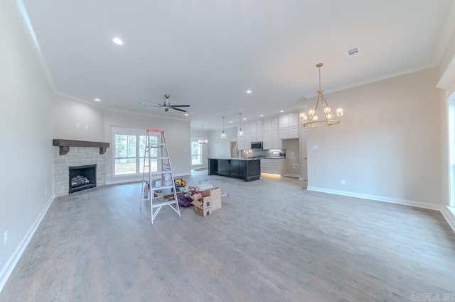 unfurnished living room with wood-type flooring, ceiling fan with notable chandelier, and crown molding