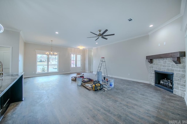 living room with ceiling fan with notable chandelier, dark hardwood / wood-style flooring, ornamental molding, and a fireplace