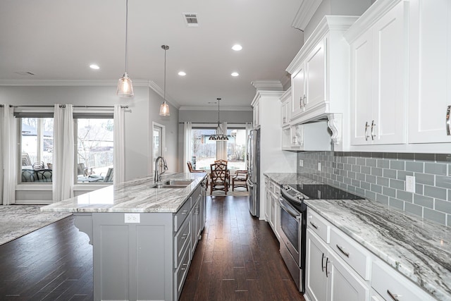 kitchen with sink, an island with sink, appliances with stainless steel finishes, decorative light fixtures, and white cabinetry