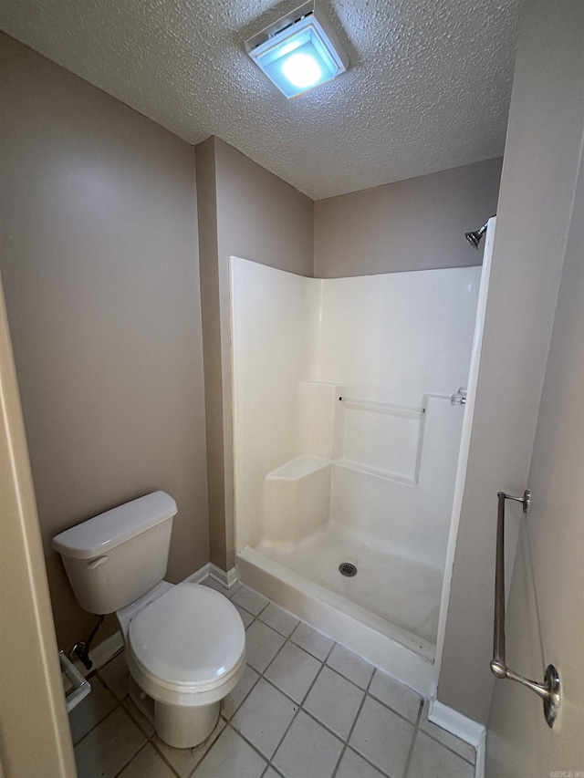 bathroom with a shower, tile patterned flooring, a textured ceiling, and toilet