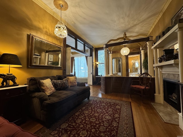 living room with a notable chandelier, wood-type flooring, crown molding, and a tile fireplace