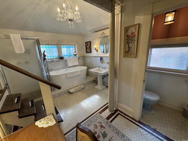 bathroom with tile patterned flooring, a chandelier, toilet, and a washtub