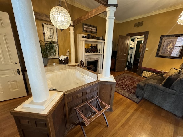 interior space featuring decorative columns, an inviting chandelier, wood-type flooring, and ornamental molding