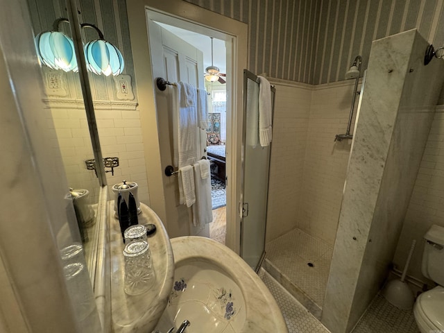 bathroom featuring ceiling fan, toilet, and tiled shower