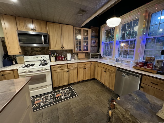 kitchen featuring sink, tasteful backsplash, decorative light fixtures, light brown cabinetry, and appliances with stainless steel finishes