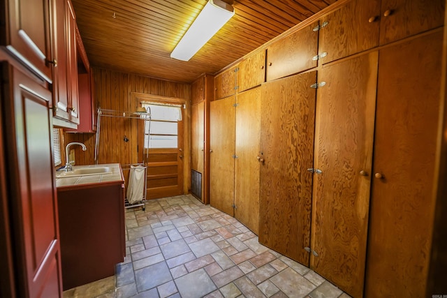 interior space with wooden walls, tile counters, sink, and wooden ceiling