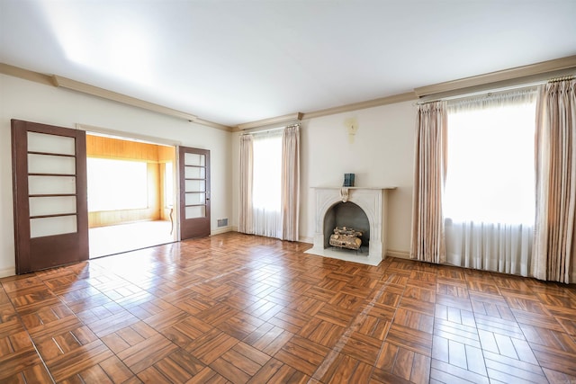 unfurnished living room featuring ornamental molding and dark parquet flooring