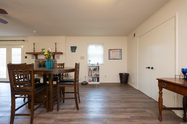 dining room with a textured ceiling, a healthy amount of sunlight, and dark hardwood / wood-style floors